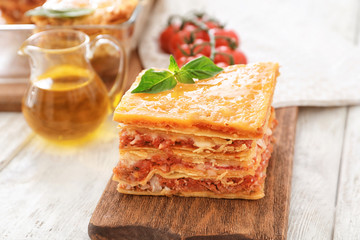Portion of tasty lasagna on wooden board