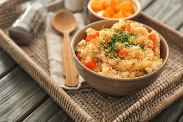 Bowl with delicious pumpkin risotto on wicker tray