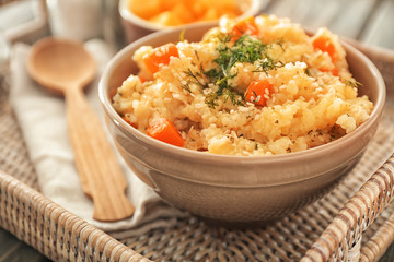 Bowl with delicious pumpkin risotto on wicker tray, closeup