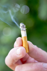 fingers holding burning cigarette pictured outdoor