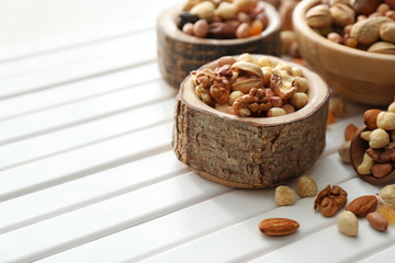 Bowl with various tasty nuts on wooden table