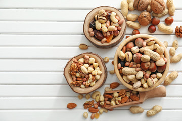 Bowls and scoop with various tasty nuts on wooden table