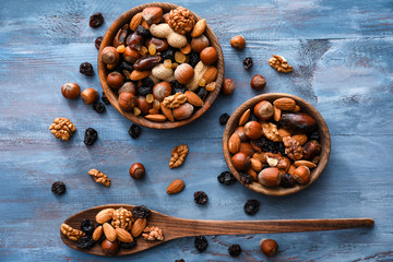 Bowls and spoon with various tasty nuts and dried fruits on wooden table