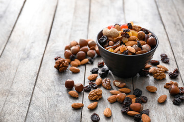 Bowl with various tasty nuts and dried fruits on wooden table