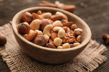 Obraz na płótnie Canvas Bowl with various tasty nuts on wooden table
