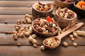 Various tasty nuts with bowls and spoon on wooden table
