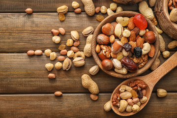 Various tasty nuts with bowl and spoon on wooden table