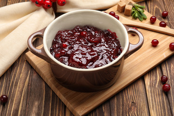 Pot with tasty cranberry sauce on table