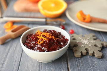 Bowl with tasty cranberry sauce on table