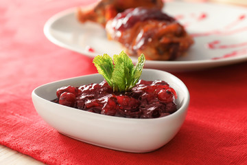 Bowl with tasty cranberry sauce on table