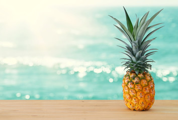 Pineapple on wooden table. Beach and tropical theme.