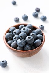 Blueberries in wooden bowl on white background. Closeup view, selective focus