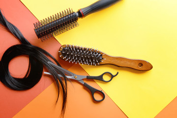 Flat lay composition with hairdresser's tools and strand of black hair on color background