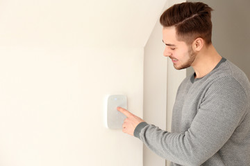 Young man entering code on security alarm system, indoors