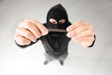 Thief putting sticky tape onto camera of alarm system, indoors