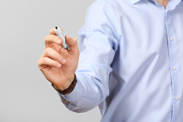 Young businessman writing on virtual screen against gray background