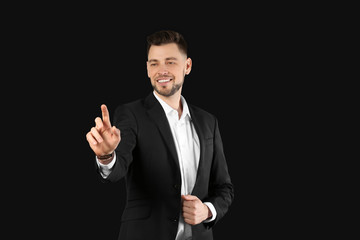 Young businessman using virtual screen on black background