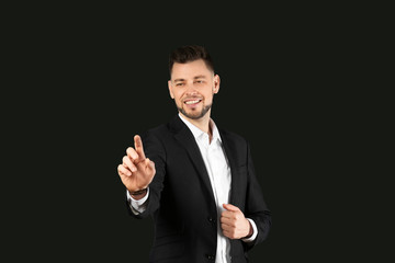 Young businessman using virtual screen on black background