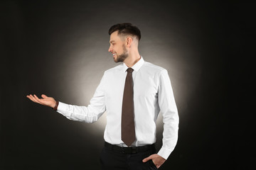 Young businessman holding something on color background