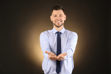 Young businessman holding something on color background