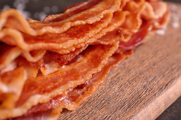 Tasty fried bacon on wooden board, closeup