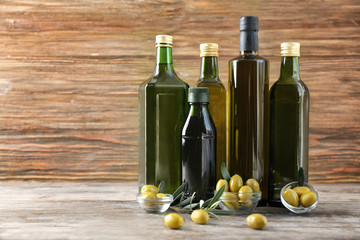 Composition with olives and oil in bottles on wooden background
