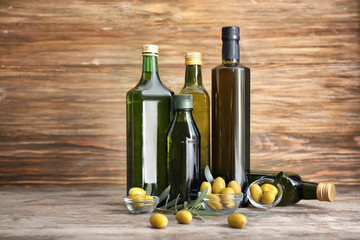 Composition with olives and oil in bottles on wooden background