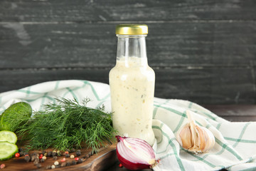 Bottle with tasty sauce and ingredients on wooden background