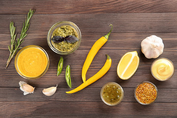 Composition with different sauces on wooden background, top view