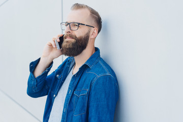 Bearded man wearing glass on a mobile phone call