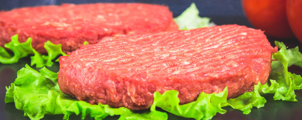 Raw burgers with lettuce on a gray background. Tomatoes, peppers