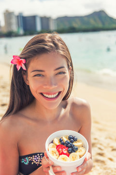 Acai bowl food healthy breakfast Asian woman eating snack on ocean background at hawaii beach. Berries and fresh fruits outdoors for a weight loss diet. Eating local Hawaiian dish.