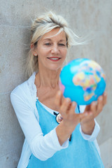 Fototapeta premium Middle-aged blond woman holding a world globe