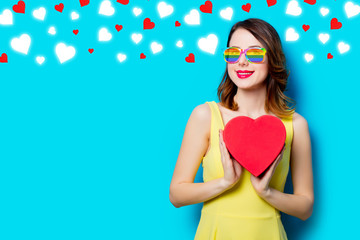 portrait of beautiful young woman with heart shaped box on the wonderful blue studio background with hearts