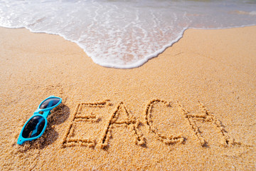 Fototapeta na wymiar Vacation concept. Word Beach written on the sand near the sea.