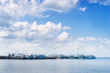 Ferry landing pier with fishing ship. Landscape with blue sea and sky.