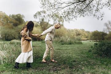 A beautiful couple in free clothes walks in the lawn near the lake on a sunny summer day