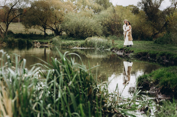 Fototapeta premium A beautiful couple in free clothes walks in the lawn near the lake on a sunny summer day