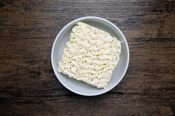 Top view of instant noodle in the glass bowl on the wooden table.