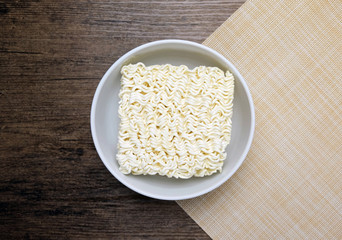 Top view of instant noodle in the glass bowl on the wooden table.