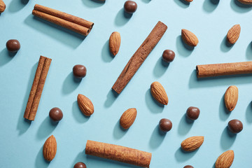 A set of ingredients for dessert, almonds, cinnamon, chocolate balls on a blue paper background flat lay. Food pattern