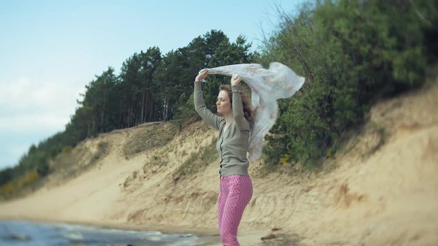 A woman listens to music on headphones, relaxes and dances on the shore of the sea river of the ocean. Technology in the open air