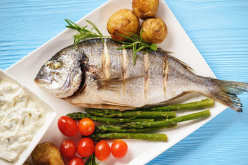 Baked dorado fish with potatoes, asparagus and tomatoes.