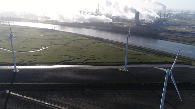 Aerial view of solar park with active wind turbines in background showing some heavy industry and nuclear power plant showing the exhaust fumes emerging from the cooling towers 4k high resolution