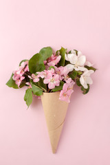 Festive flower apple tree composition in craft horn on the pastel pink background. Overhead view