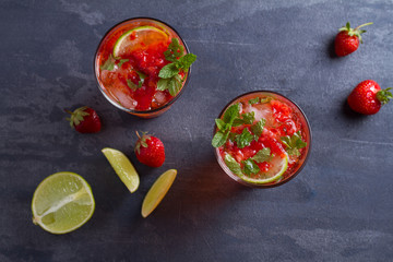 Strawberry mojito cocktail with berries, lime, mint and ice. Summer berry cocktail. View from above, top studio shot