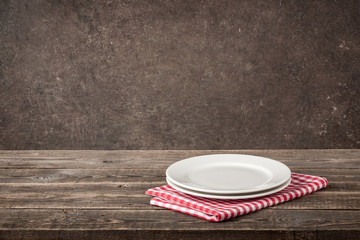 Two plate and red-white checkered napkin on wooden table