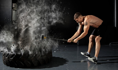 man hitting wheel tire with hammer sledge
