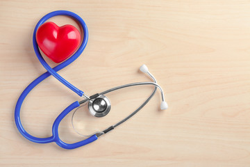 Stethoscope with small heart on wooden background