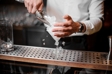 Bartender adding crushed ice into an empty cocktail glass